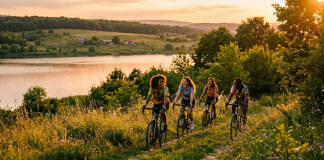 Tineri cu biciclete pe un traseu în natură la apus, ilustrând activități outdoor în Iași lângă un lac.