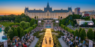 Prezentare de modă Romanian Fashion Week în Grădinile Palas la asfințit, cu Palatul Culturii luminate în fundal și public numeros, ilustrând lucruri de făcut seara în Iași.